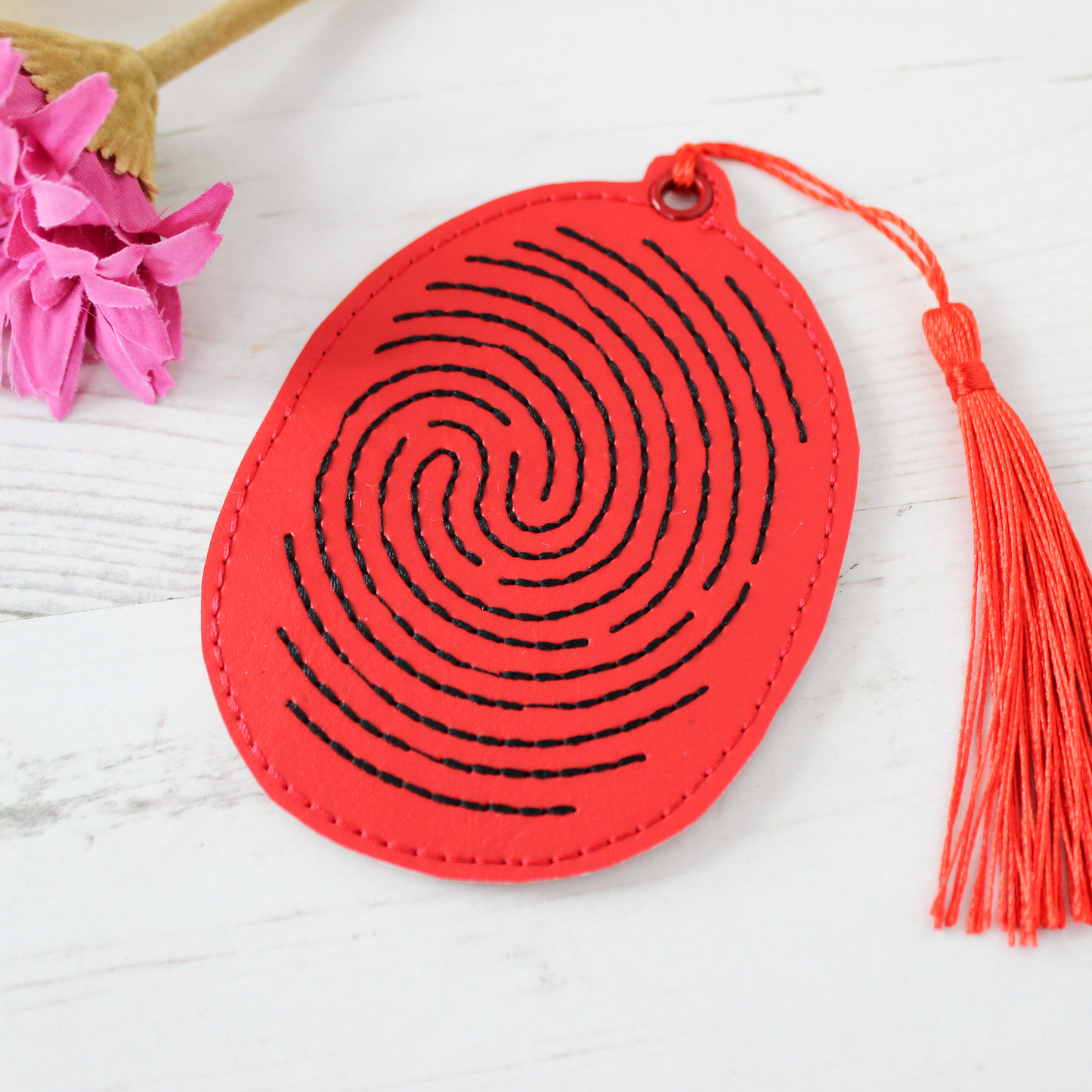 Red circular object with black spiral design and orange tassel on a white background