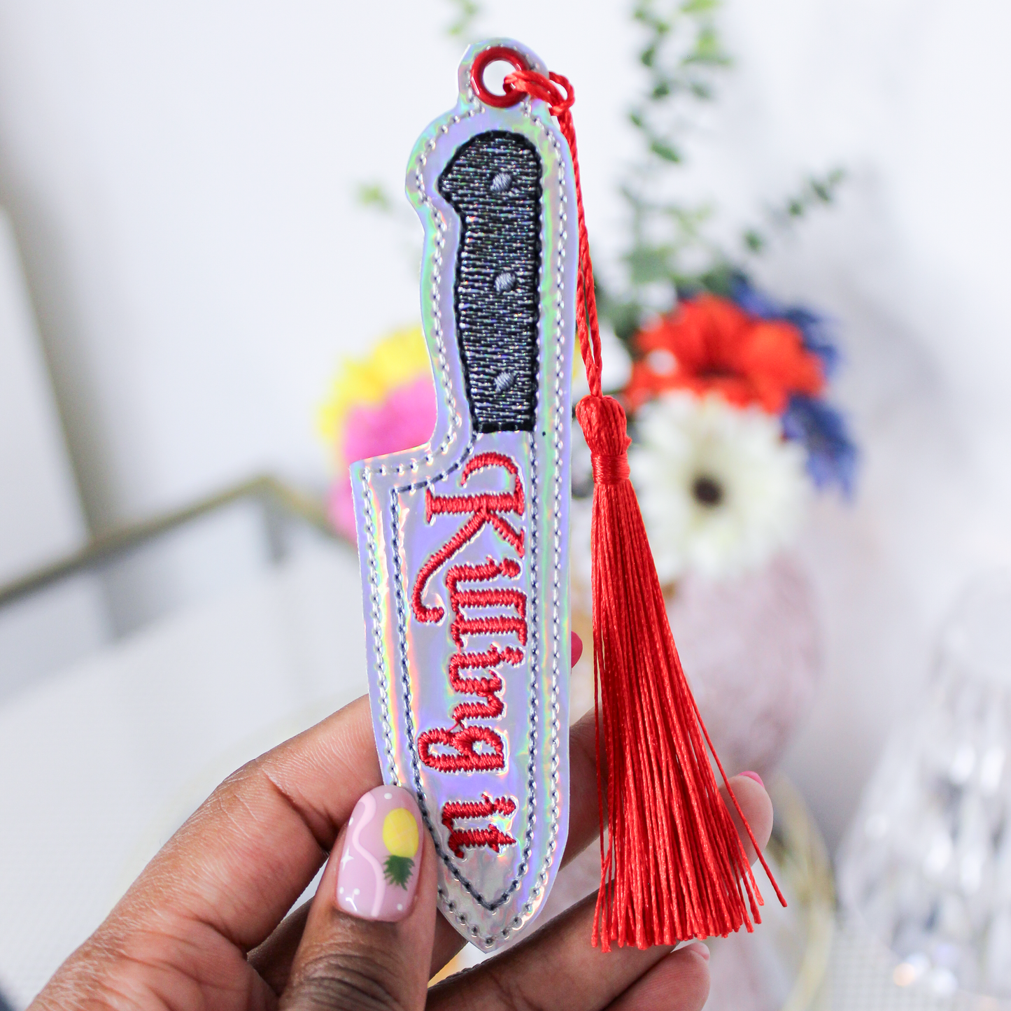 Keychain with knife design and 'Killing it' text, held by a hand with colorful nail polish.