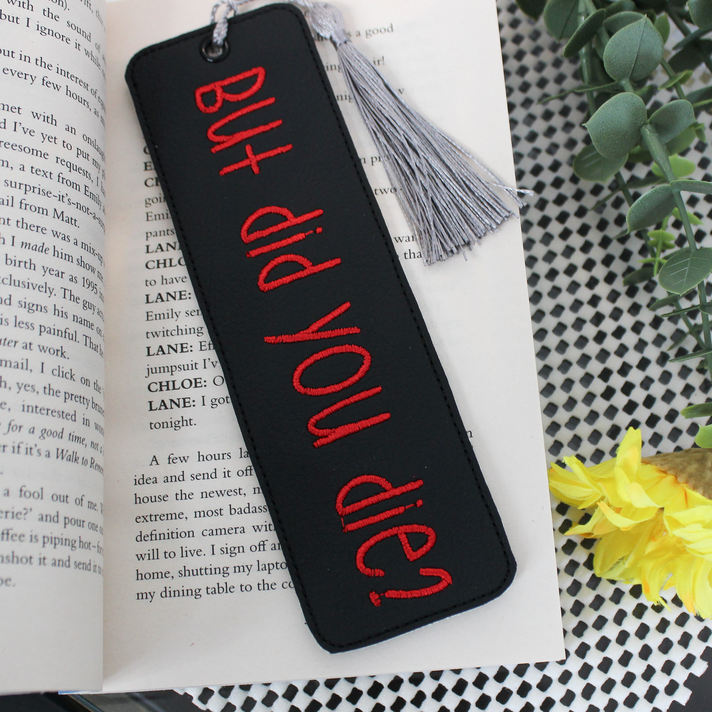 Black bookmark with red text 'BUT did YOU die?' on an open book with a tassel.