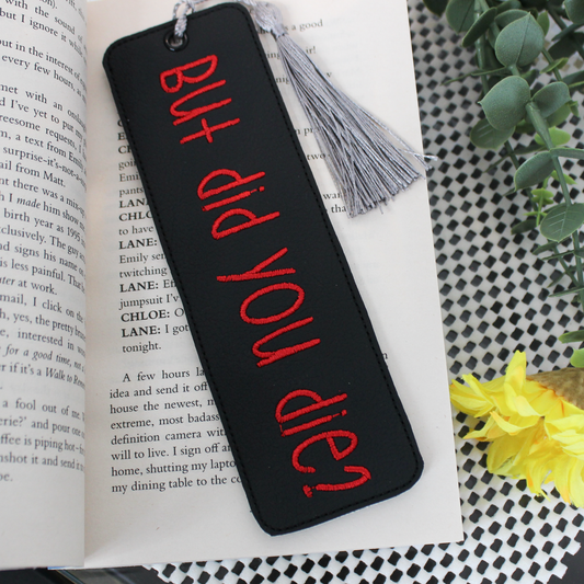 Black bookmark with red text 'BUT did YOU die?' on an open book with a tassel.