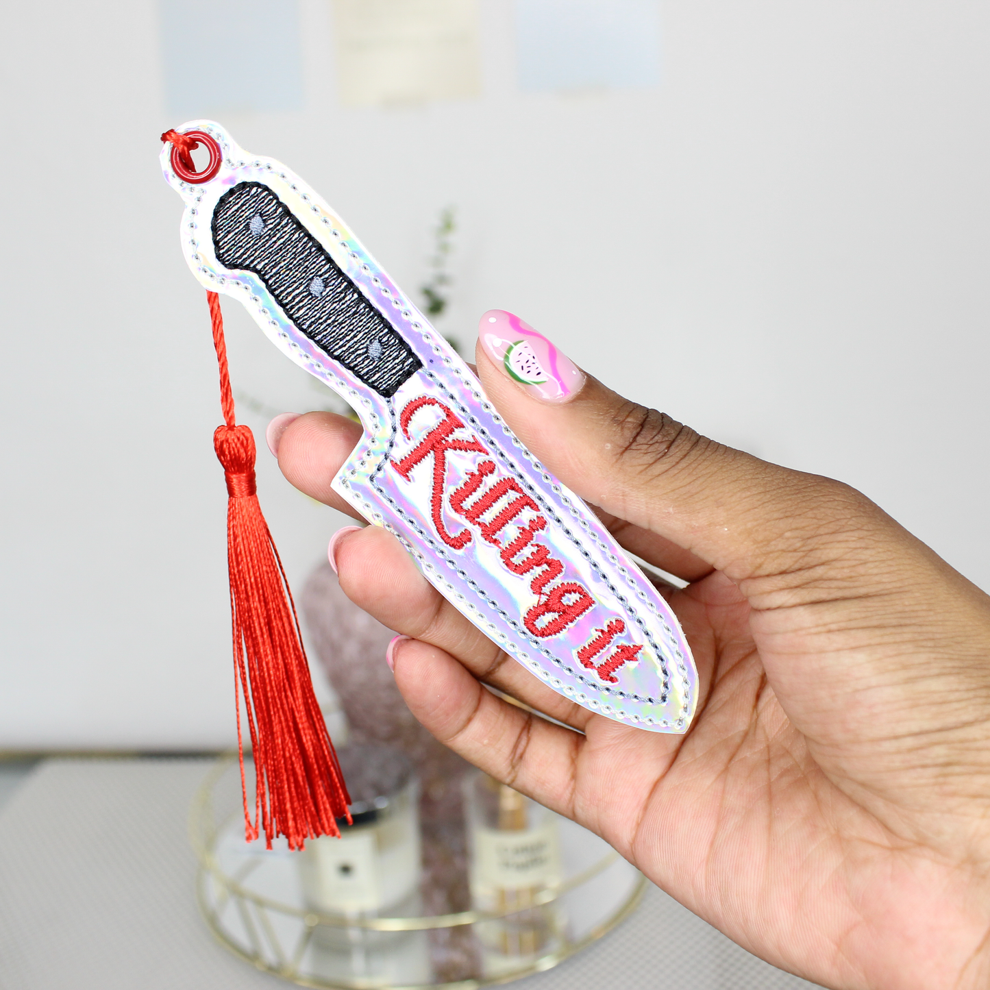 Hand holding a decorative Knife Shaped bookmark with 'Killing It' text and a red tassel.
