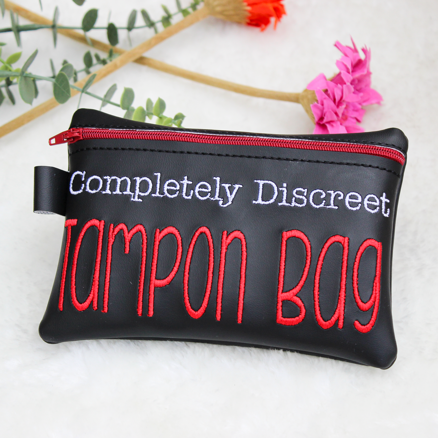 Black tampon bag with red and white text on a light background
