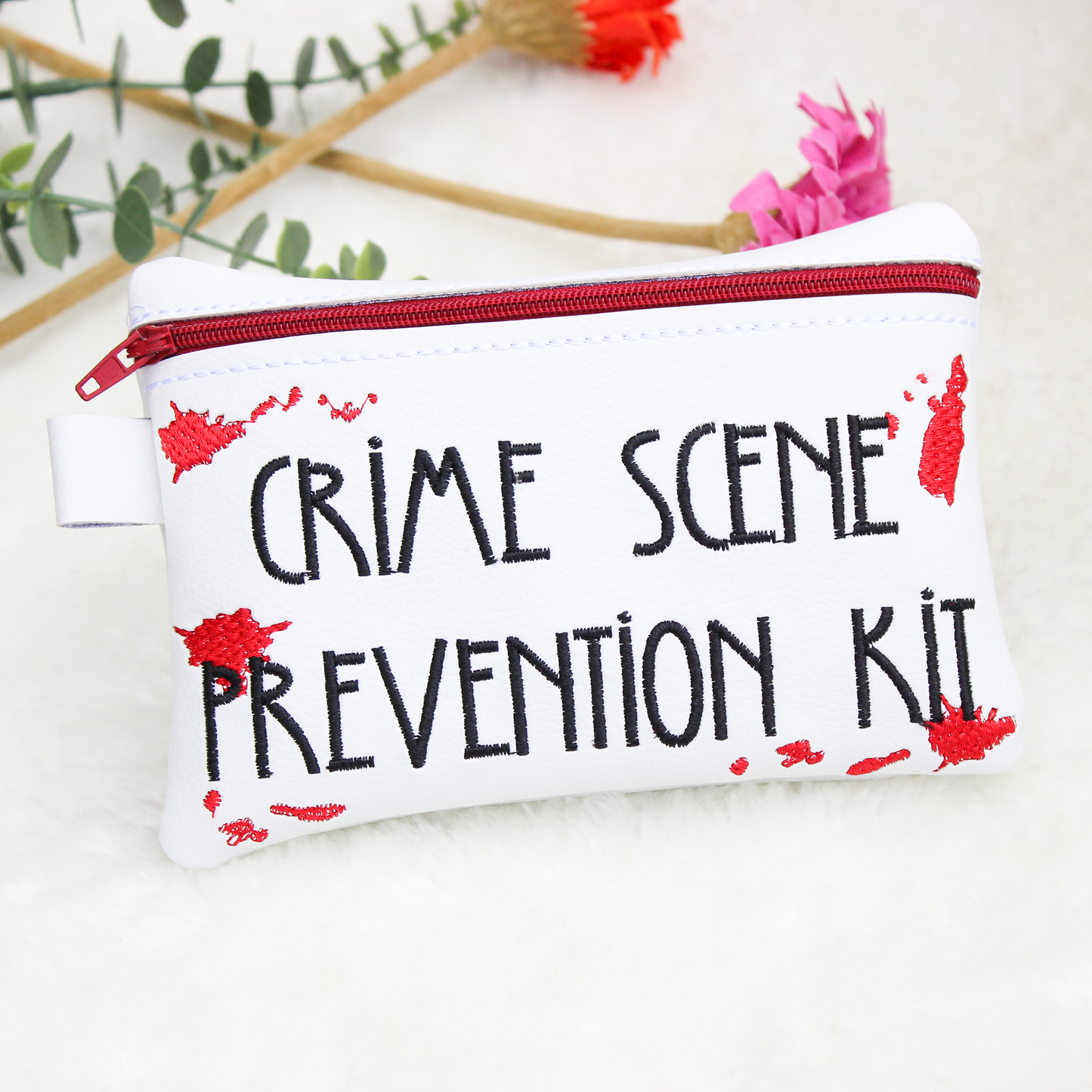White pouch with 'Crime Scene Prevention Kit' text on a white background with flowers.