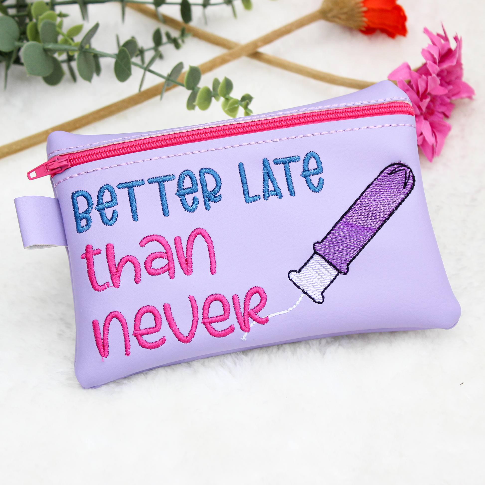 Purple pouch with 'Better Late than Never' text and a tampon on a white background.