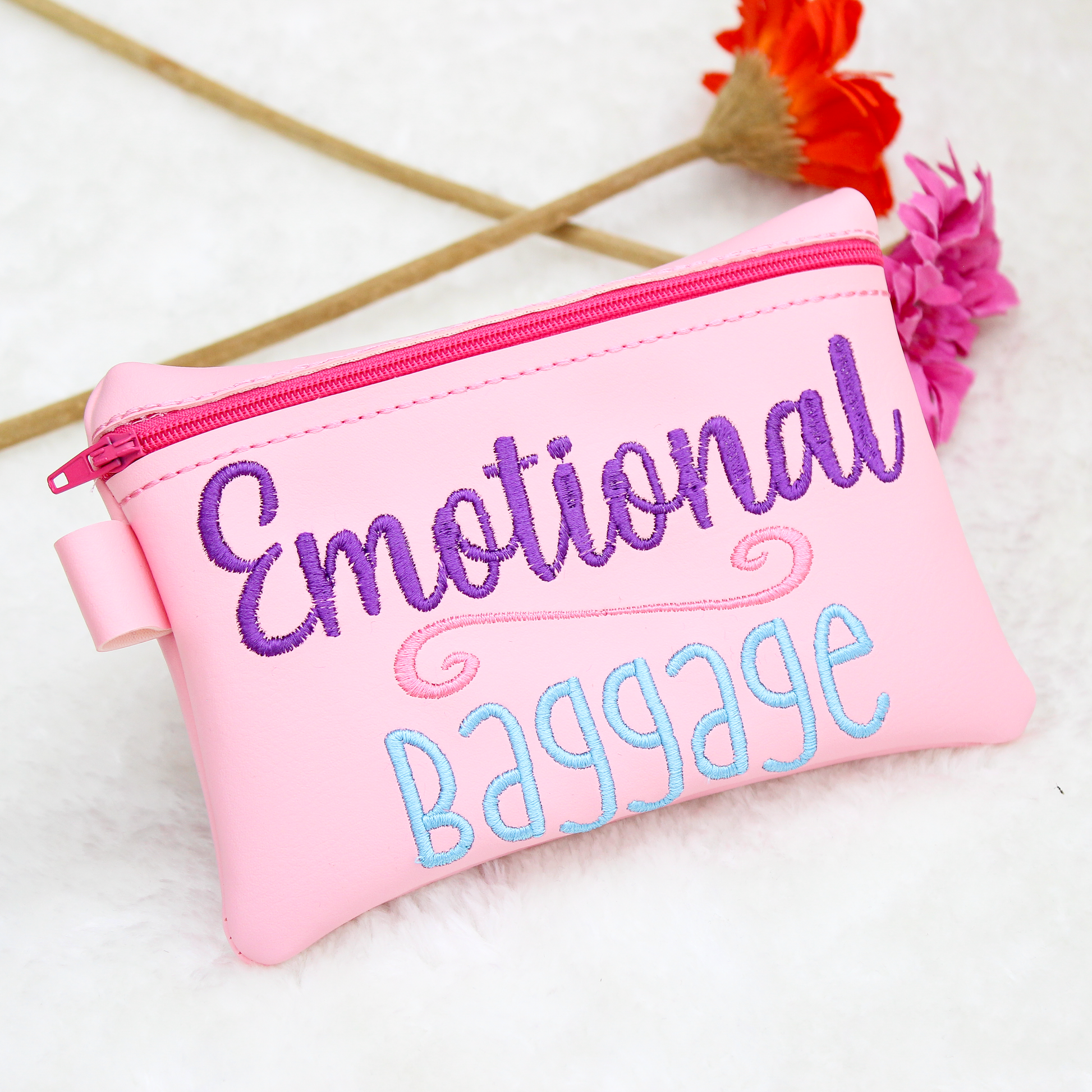 Pink pouch with 'Emotional Baggage' text on a white background with flowers.
